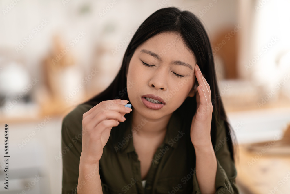 Unhappy asian woman suffering from headache, taking pill Unhappy asian woman suffering from headache, taking pill