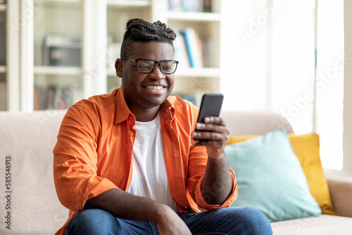 Smiling young black man wearing eyeglasses using cell phone