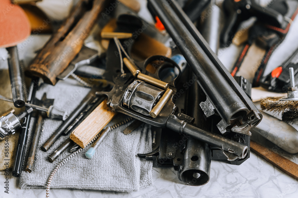 Weapons, a rifle with ammunition, a revolver with cartridges, parts and accessories close-up lie on the table. Close-up photo.