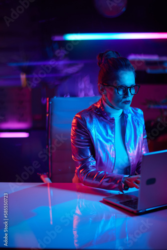 pensive trendy woman in glasses with laptop in modern office