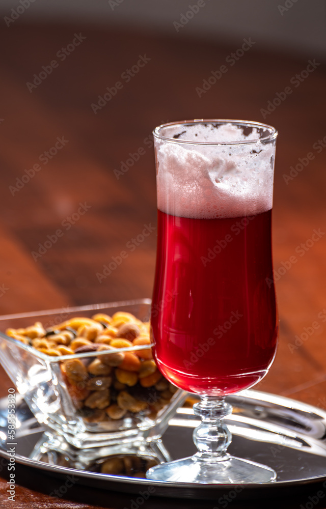 Glass of Belgian fruity red sour cherry kriek beer and party mix nuts, pairing of food and beer in Belgium Glass of Belgian fruity red sour cherry kriek beer and party mix nuts, pairing of food and beer in Belgium