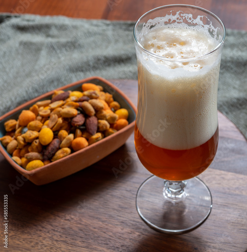 Glass of Belgian light blond beer made in abbey and bowl with party mix nuts