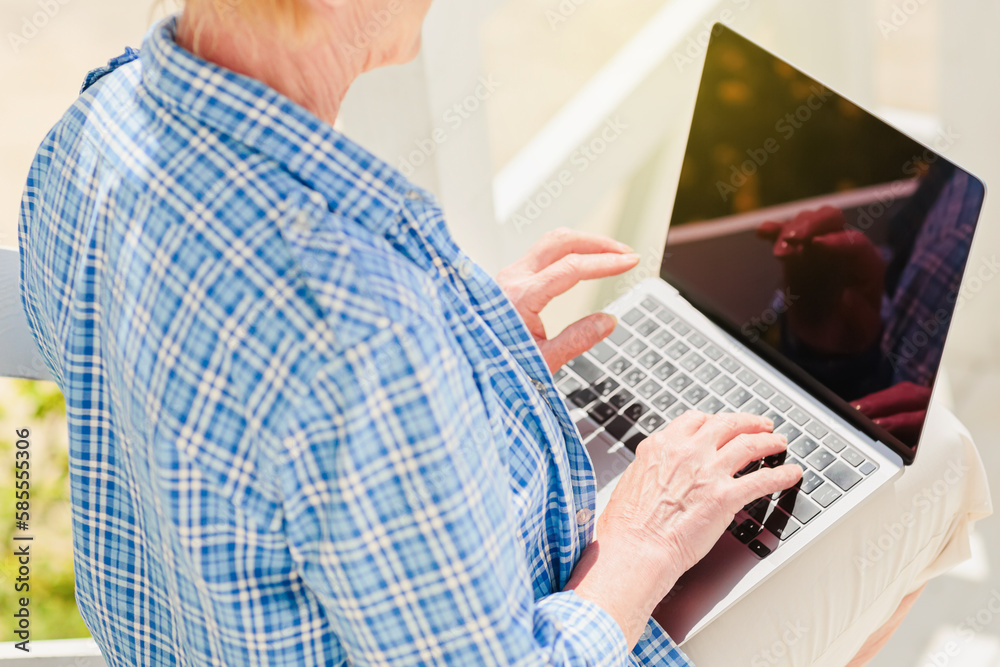 Unrecognizable senior adults woman using laptop for distance learning education outdoors. Confident real woman working in distance