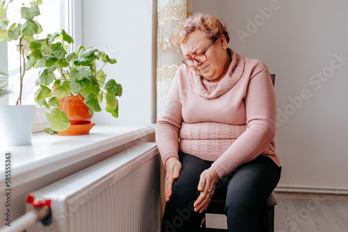 Painful Struggle An Overweight Woman Suffers with Leg Pain at Home, A senior woman holding onto her leg, wincing in pain due to leg ache, a reminder of the struggles of aging and being overweight