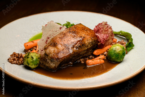 Close-up view on dish of piece of baked pork meat with buckwheat and vegetables on plate