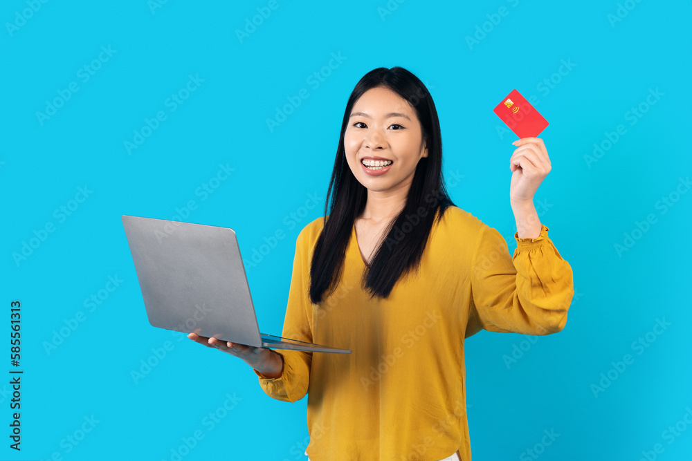 Happy asian woman holding laptop and bank card Happy asian woman holding laptop and bank card