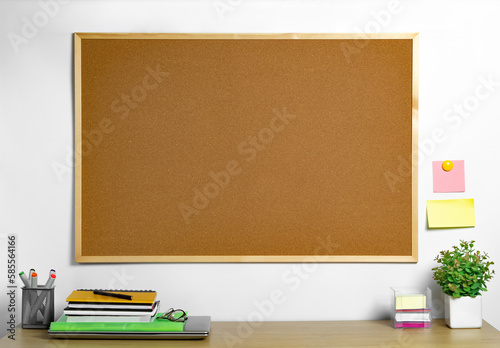 Empty cork board with wood frame over work desk. Place for notes and reminders.