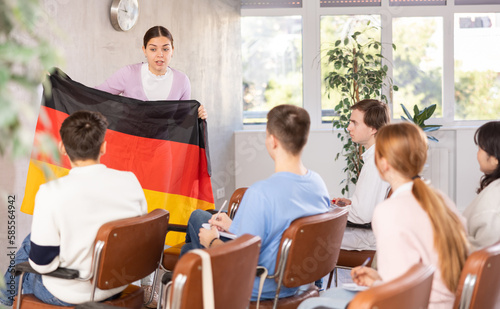 Female teacher tells the history of the state of Germany  holding the national flag of Germany in his hands