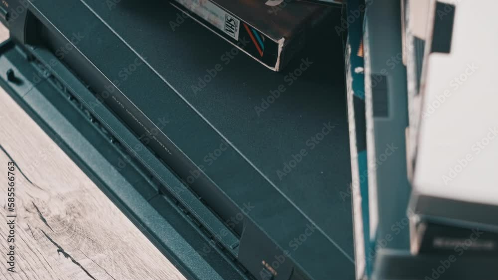 Eject VHS tape cassette from VCR player. Male hand pushes a button and