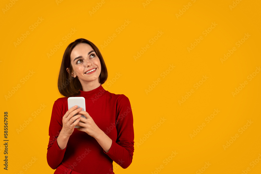 Curious young brunette woman using smartphone on orange Curious young brunette woman using smartphone on orange