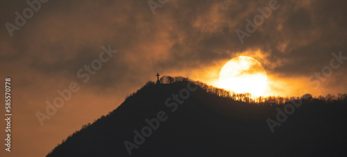 Image of the cross on top of Mount Musinè with a sun frame 