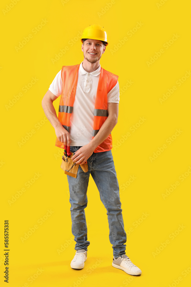 Male worker in vest on yellow background