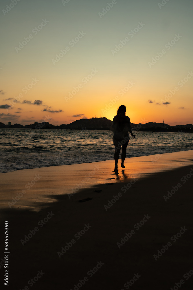 beautiful woman enjoying the beach and an incredible sunset against light