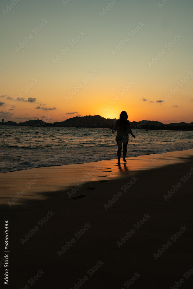 beautiful woman enjoying the beach and an incredible sunset against light beautiful woman enjoying the beach and an incredible sunset against light