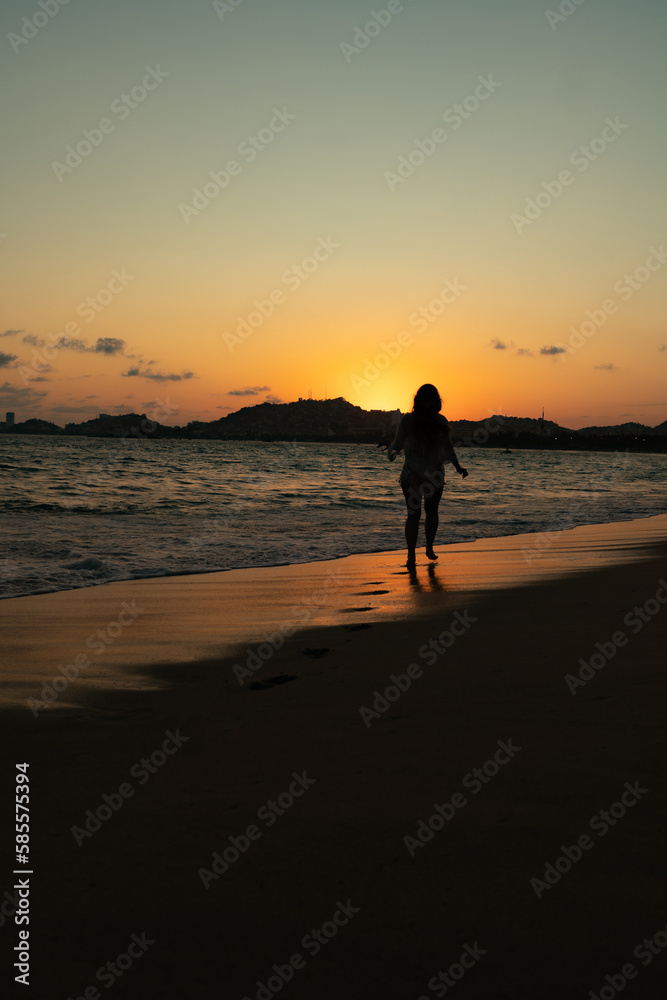 beautiful woman enjoying the beach and an incredible sunset against light