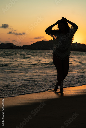 beautiful woman enjoying the beach and an incredible sunset against light