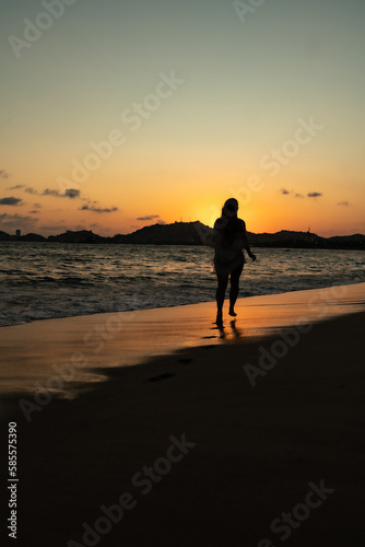 beautiful woman enjoying the beach and an incredible sunset against light