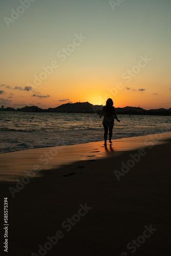 beautiful woman enjoying the beach and an incredible sunset against light