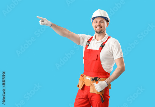 Male carpenter with hammer pointing at something on blue background