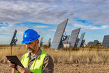 Castilla y León, Spain. Solar panel engineer next to solar energy farm checking operation on digital tablet