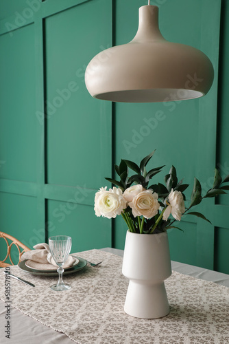 Vase with ranunculus flowers on dining table in room