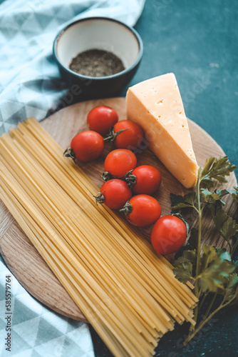 Italian food cooking-tomatoes, basil, pasta and cheese on stone background, top view, copy space