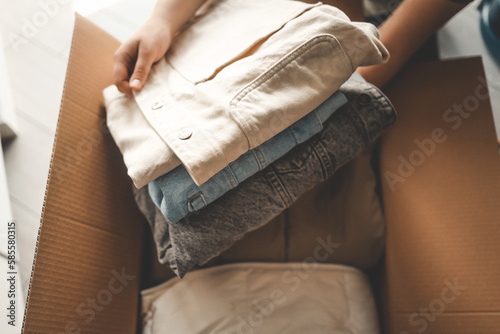 Obraz na plátně Woman holding Clothes with Donate Box In her room, Donation Concept