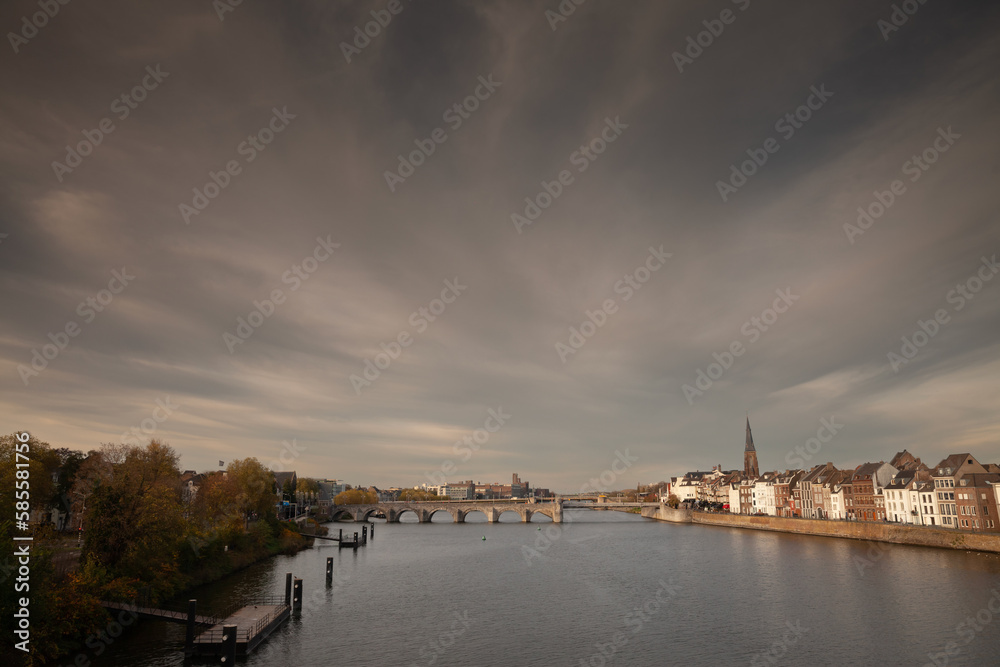 Panorama of Maastricht Waterfront on the Meuse Maas river with a focus on sint servaasbrug or saint servatius bridge, in autumn, during a sunny sunset. Maastricht is a dutch city in the netherlands in
