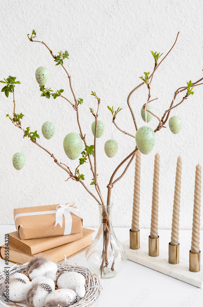 Vase with tree branches, Easter eggs, books and gift box on table near light wall, closeup Vase with tree branches, Easter eggs, books and gift box on table near light wall, closeup