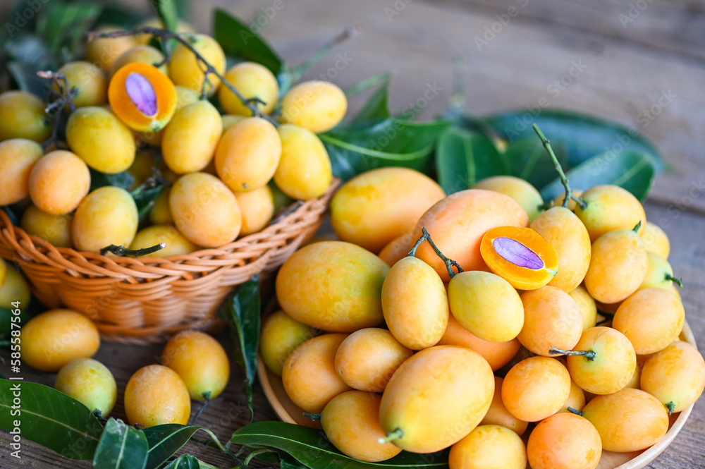 Marian plum fruit and leaves in basket on wooden background, tropical fruit Name in Thailand Sweet Yellow Marian Plum Maprang Plango or Mayong chid