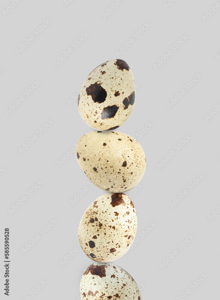 Stacked speckled quail eggs on light grey background Stacked speckled quail eggs on light grey background