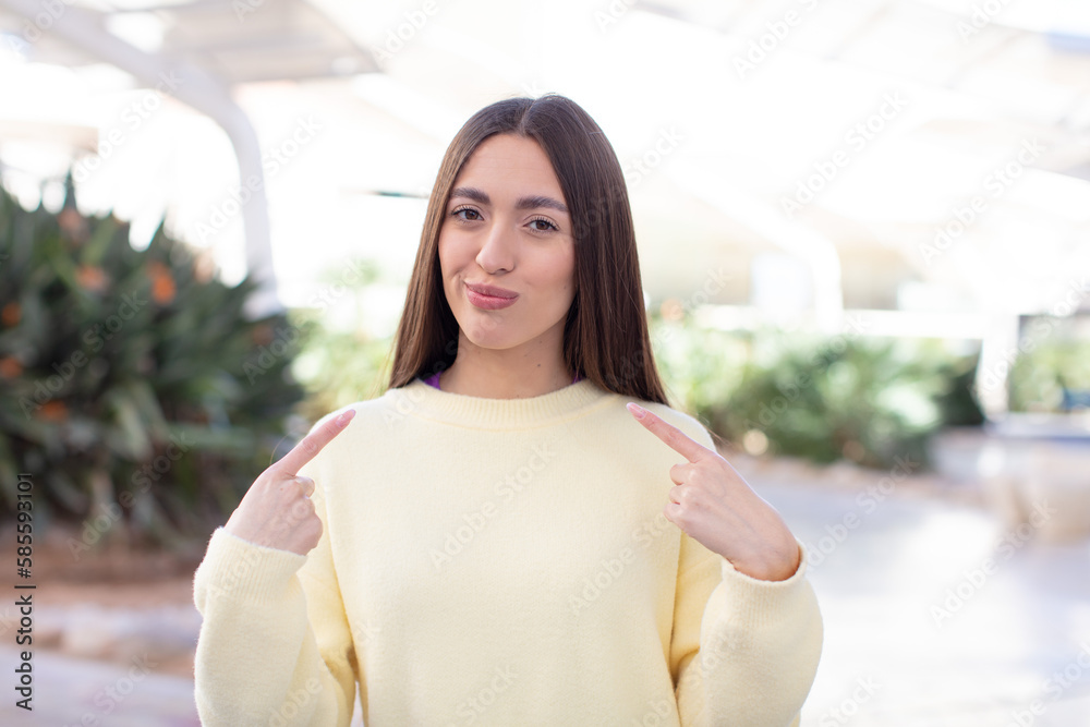 young pretty woman with a bad attitude looking proud and aggressive, pointing upwards or making fun sign with hands