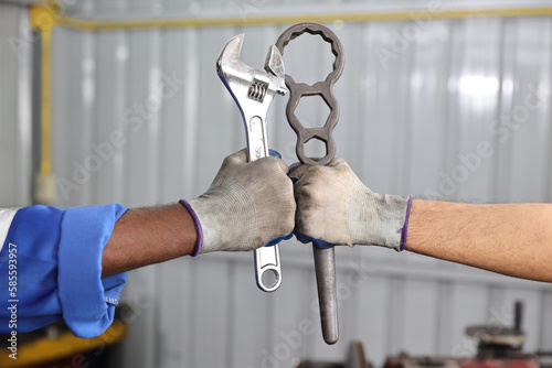 Technicain mechanic hands holding wrench and make fist bumping celebrate successful together completed deal commitment at garage. Maintenance automotive and inspecting vehicle part concept photo