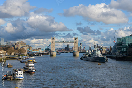 Tower Bridge and HMS Belfast on the River Thames in London with partly cloudy blue sky