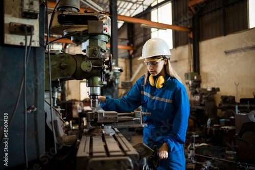 Woman worker operating a machine tool in metal factory. photo