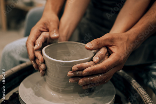 Couple mold ceramic vase in a pottery workshop, hands close up.