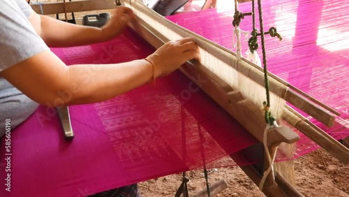 Close up of a woman on a loom to produce Fuchsia Pink Thai silk, by alternating silk threads left and right, Traditional silk production on the Thai countryside. photo