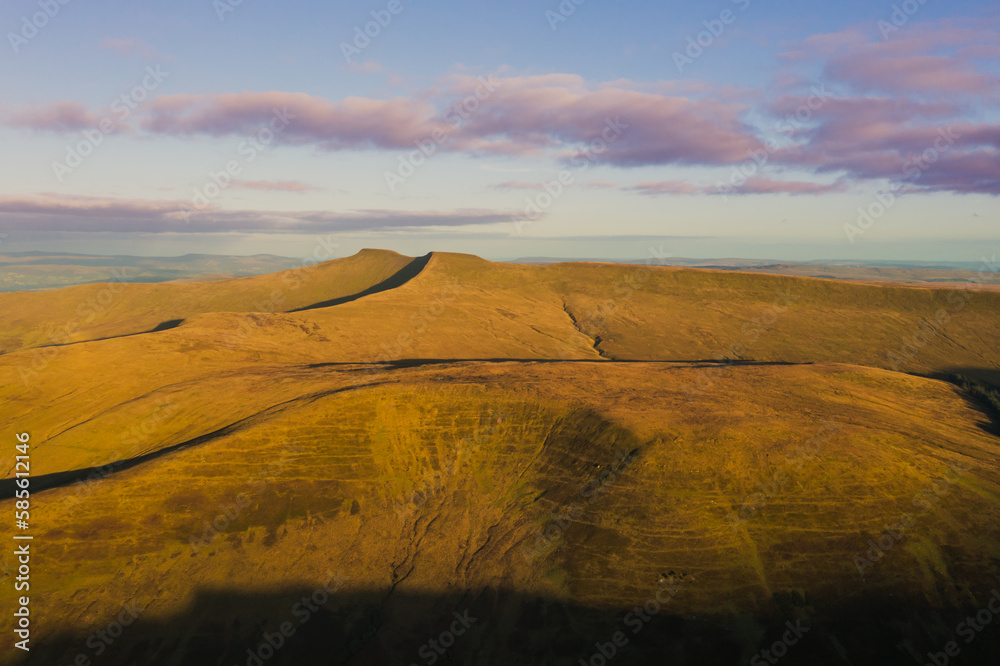 Expansive view of the Brecon Beacons at sunrise showcasing golden hills under a colorful sky in Wales Expansive view of the Brecon Beacons at sunrise showcasing golden hills under a colorful sky in Wales
