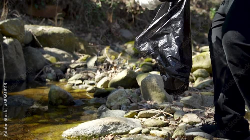 Man activist clean up plastic waste, littering rubbish in a river in a forest, promote environmental awareness, reuse recycle concept, plastic waste in the water with trees in nature, eco friendly act Man activist clean up plastic waste, littering rubbish in a river in a forest, promote environmental awareness, reuse recycle concept, plastic waste in the water with trees in nature, eco friendly act