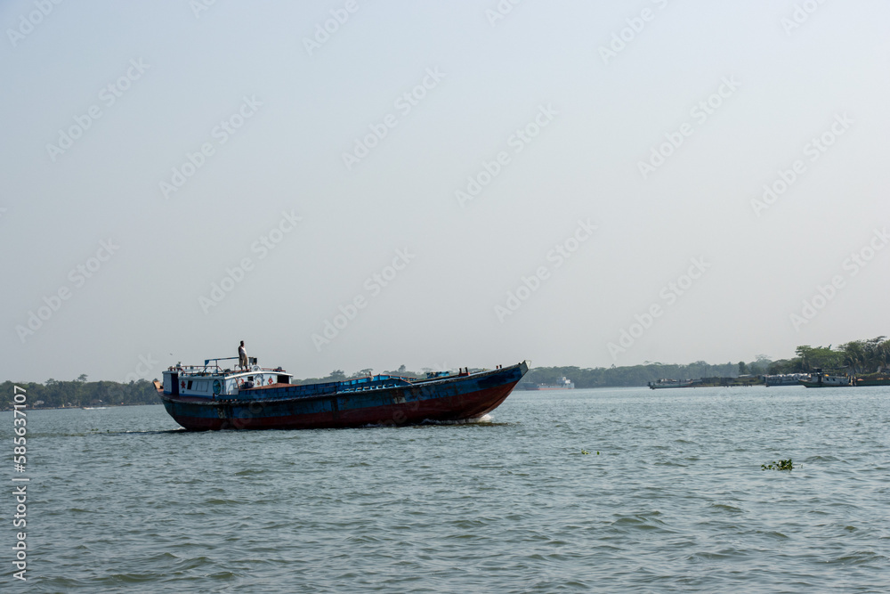 Troller boat on the river delivering goods close-up photo. Beautiful rural area and water vessel transportation. Beautiful sky and river horizon scenery with a motorboat. Restless river and blue sky.