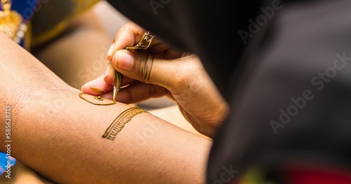 Henna Artist applying henna tattoo on women hands