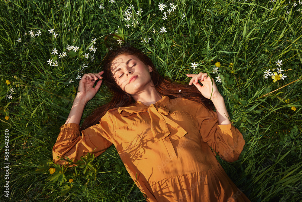 a relaxed woman, resting lying in the green grass, in a long orange dress, with her eyes closed and a pleasant smile on her face, recuperating, illuminated by the warm rays of the setting summer sun a relaxed woman, resting lying in the green grass, in a long orange dress, with her eyes closed and a pleasant smile on her face, recuperating, illuminated by the warm rays of the setting summer sun