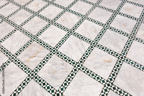 Typical moroccan tiles in the floor in the shape of a white and green square in a riad in marrakech, morocco