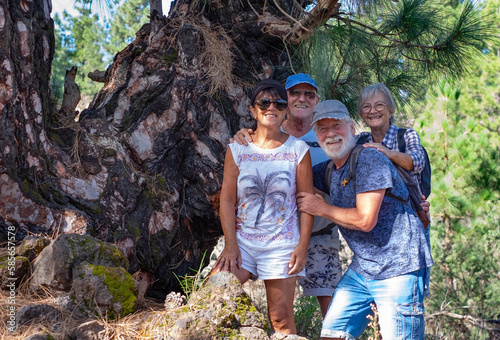Cheerful group of senior people looking at camera while enjoying a mountain hike in the forest appreciating leisure and freedom, beautiful retired seniors and healthy lifestyle concept