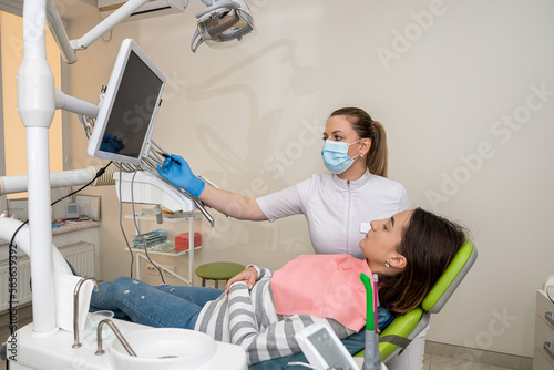 Female doctor use intro oral dental camera and watch on the monitor live picture of teeth her patient