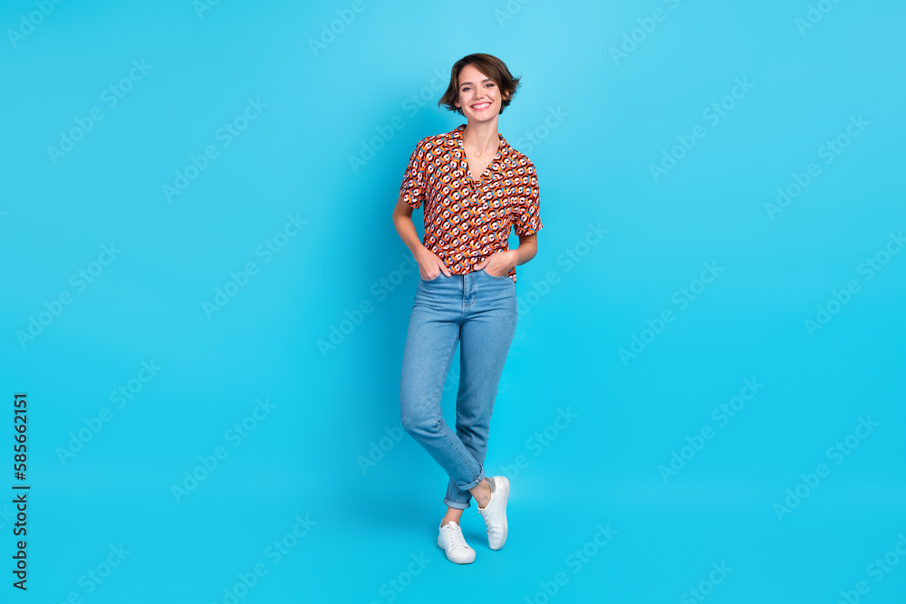 Full size portrait of satisfied glad young girl put hands pockets isolated on blue color background Full size portrait of satisfied glad young girl put hands pockets isolated on blue color background