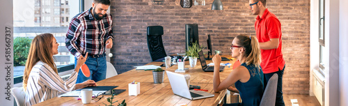 Colleagues talking in office while two of them having fun playing ping pong over coworking table