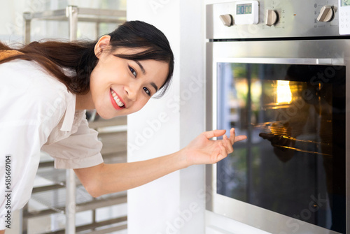 Woman Baking In Oven . young pretty woman warming prepare oven to cook or baking. domestic kitchen concept