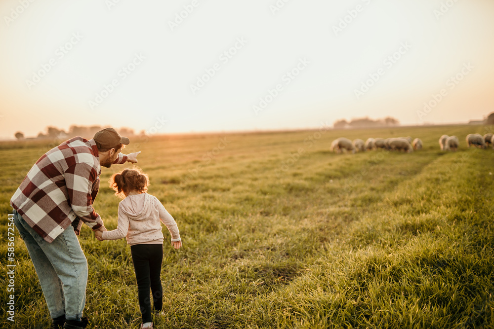 Happy family on holiday vacation. Smiling father and little daughter holding hands and walking together on the meadow field. Parent with child girl relax and enjoy an outdoor lifestyle. Copy space