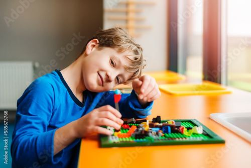 Little boy playing with plastic brick children's constructor at home.